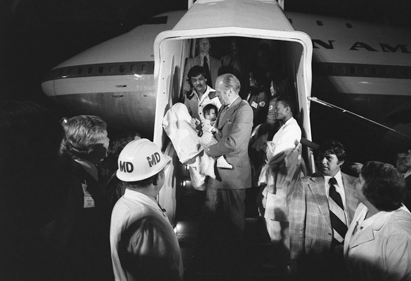 Pres. Gerald Ford carries a Vietnamese baby from Pan Am Clipper during Operation BabyLift, April 3-26, 1975